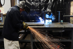 Inmates operating welding equipment to weld metal together